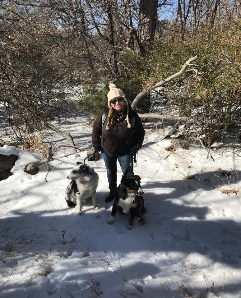 Charyl, a Tender Hearts Dog Rescue teammate, and her two dogs standing in a snowy forest.